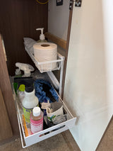 Compact rv rental cabinet featuring slide-out baskets neatly organizing cleaning supplies, toilet paper, and toiletries.