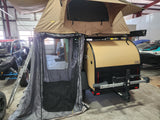 Teardrop trailer with rooftop tent and annex setup, ideal for rv rental adventures. UTV & jet ski also shown in garage.