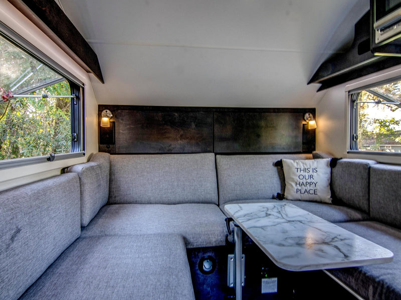  parked on grass. Ideal for camping; features a spare tire & storage box.|Inside an rv rental: compact kitchen with microwave — photo 10