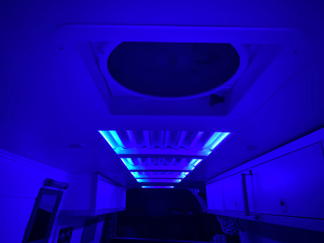 Immerse in the vibrant blue glow of this RV rental's interior. Featuring ambient ceiling lights, a roof vent, and practical overhead storage.