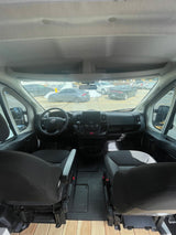 Inside an RV rental: the front cabin shows two seats, a steering wheel, and dashboard. A wooden floor is visible.