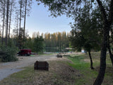 This red RV rental enjoys a tranquil lake campground spot, surrounded by tall pines, offering docks for water activities.