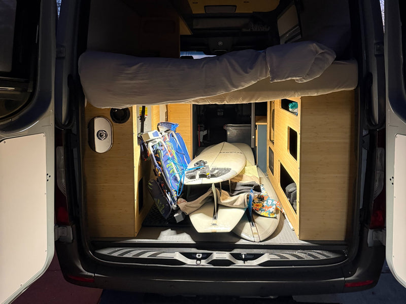  facing the ocean where a person wades.|Inside an RV rental van: rear view showing a comfy raised bed — photo 7