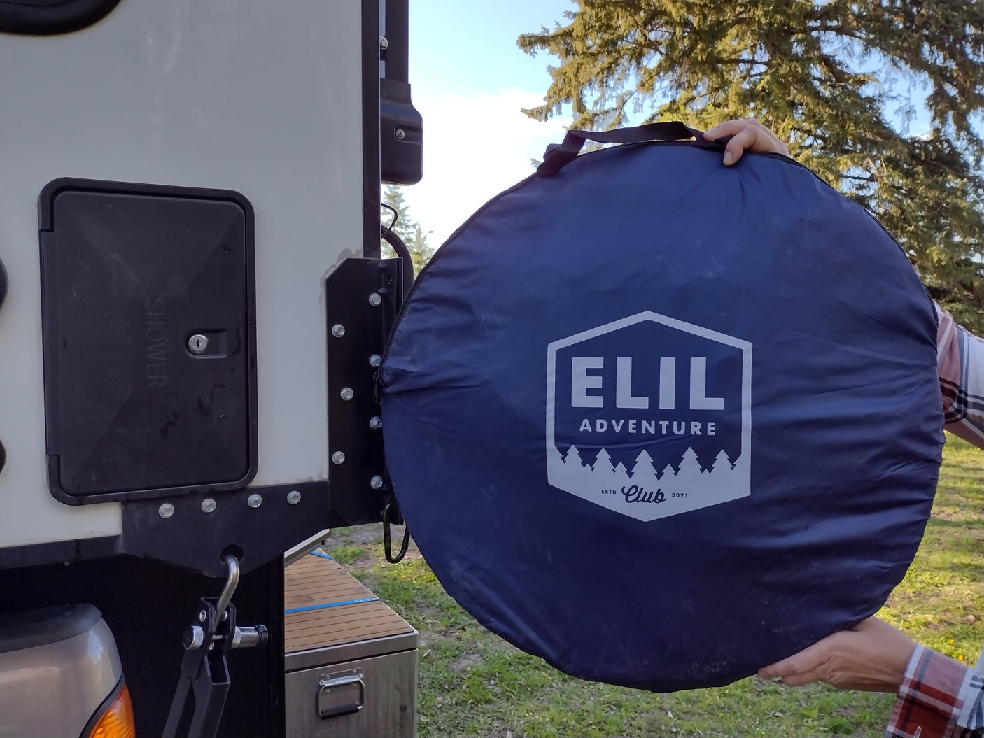 Unpacking an Elil Adventure portable shower tent by an RV rental's exterior shower panel. Perfect for camping!