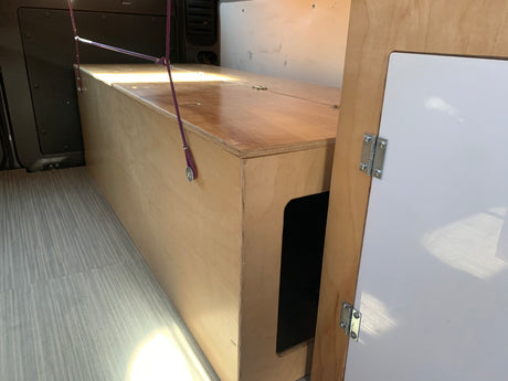 This RV rental features a practical wooden storage box or bed platform, maximizing space inside a camper van.