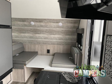 A cozy RV rental dinette featuring two upholstered benches, a table, and partial views of a fridge and stove.