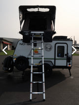 Compact travel trailer RV rental with open rooftop tent & ladder, ready for your next outdoor adventure.