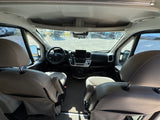 Spacious RV rental cockpit: front seats, modern dashboard, and an outdoor view of other RVs in a lot.