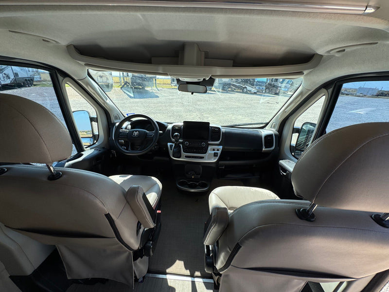 Spacious RV rental cockpit: front seats, modern dashboard, and an outdoor view of other RVs in a lot. — photo 4