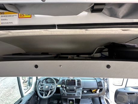 RV rental camper van interior, featuring the pop-top sleeping roof with safety warnings & the driver's cabin with dashboard controls.