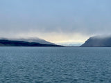 Serene fjord framed by misty mountains under a pale sky. Discover with an RV rental.