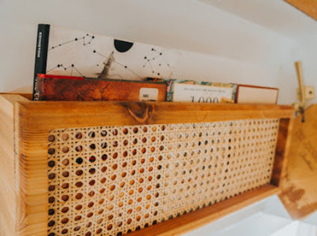 Stylish wooden shelf with books & woven cane detail in an RV rental. Perfect storage for organized travels.
