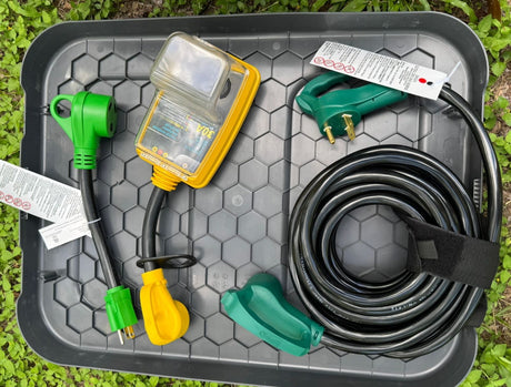 RV rental power essentials: 30A circuit analyzer, coiled black power cord, and green/yellow adapters. On a gray tray.