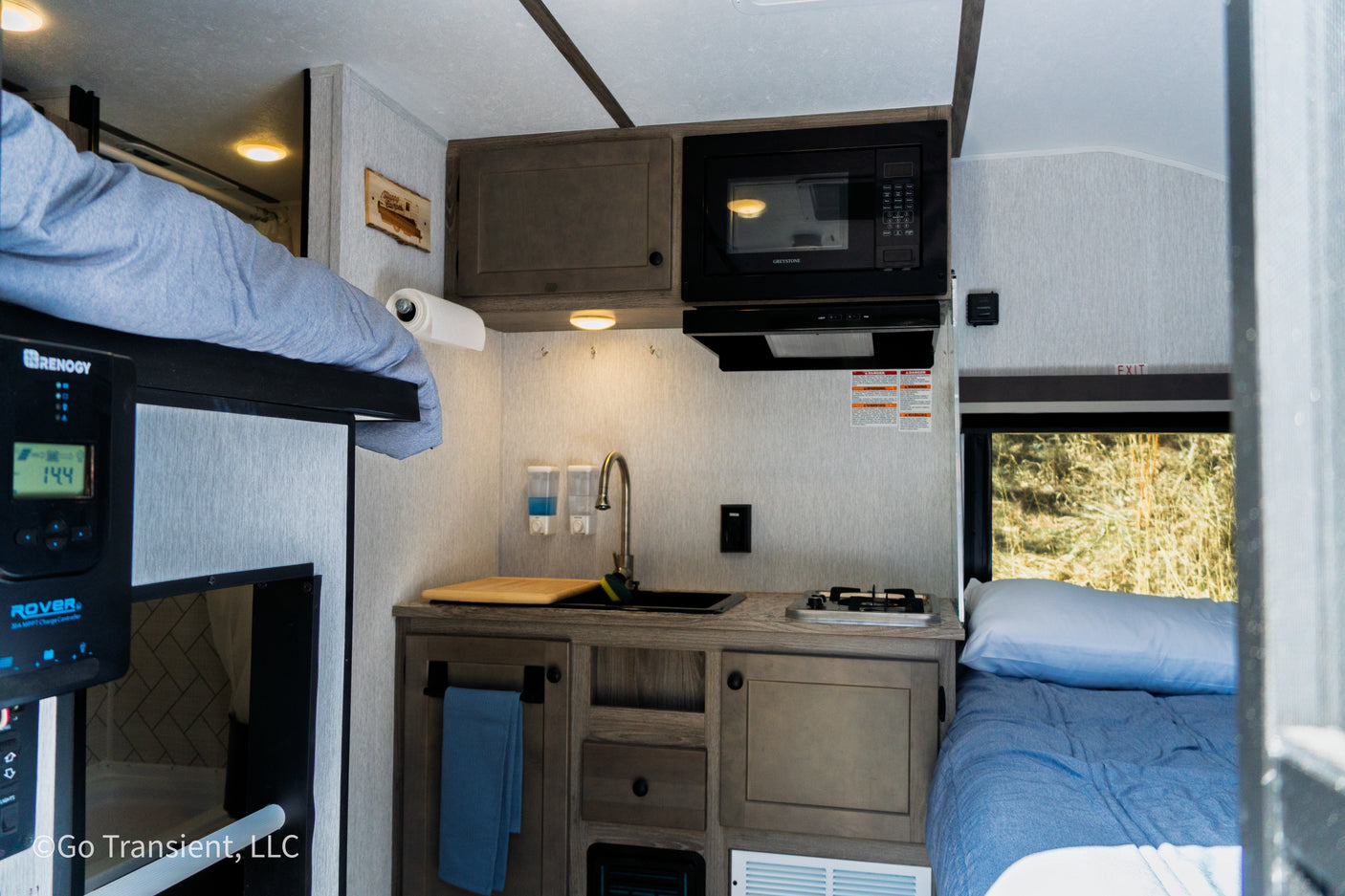 This RV rental showcases a compact interior with a kitchen, bunk, and bed, optimized for travel comfort.