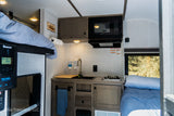 This RV rental showcases a compact interior with a kitchen, bunk, and bed, optimized for travel comfort.