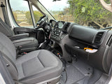 Inside an RV rental van's front cabin, showing the dashboard, steering wheel, and seats with a view out the windows.