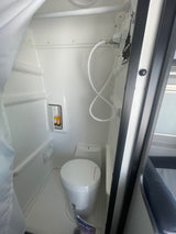 Inside an RV rental: a compact wet bath with toilet, handheld shower, and storage for toiletries.