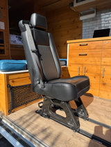 RV rental interior with a versatile passenger seat on floor rails, complementing the custom wooden cabinets and cozy living space.