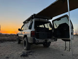 Overland SUV, awning deployed, open rear hatch at desert sunset. Perfect for camping, similar to an RV rental experience!