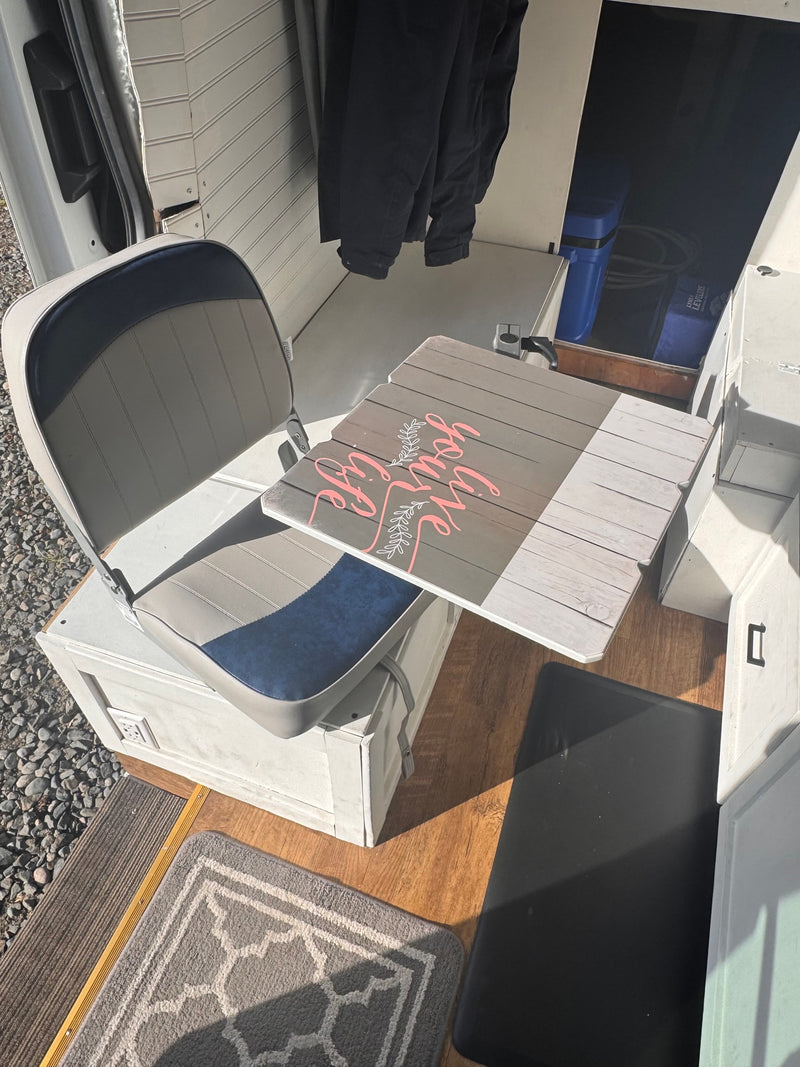  an ideal rv rental. It's parked on asphalt next to a green hill under a blue sky.|This RV rental interior shows a custom camper van setup with a water heater — photo 8