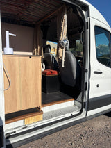 View inside an rv rental camper van: custom kitchenette, patterned ceiling, & a fun disco ball near the driver's seat.