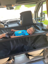 Smiling boy in an RV rental's front hammock bed, a cozy extra sleeping spot in the cabin.