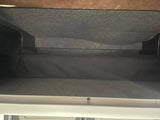 Spacious gray overhead storage in an RV rental, featuring textured walls and a dark fabric base.