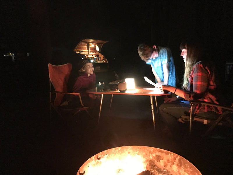 Night camping with an RV rental: people gathered around a table with a lantern, warmed by a campfire. — photo 16