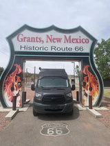 RV rental van at Historic Route 66 entrance in Grants, New Mexico. A dark van is parked under the iconic shield sign.