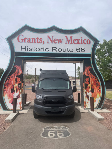 RV rental van at Historic Route 66 entrance in Grants, New Mexico. A dark van is parked under the iconic shield sign.