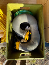 Green crate of RV rental essentials: white sewer hose, green water hose, yellow electrical cord—all for easy camping hookups.