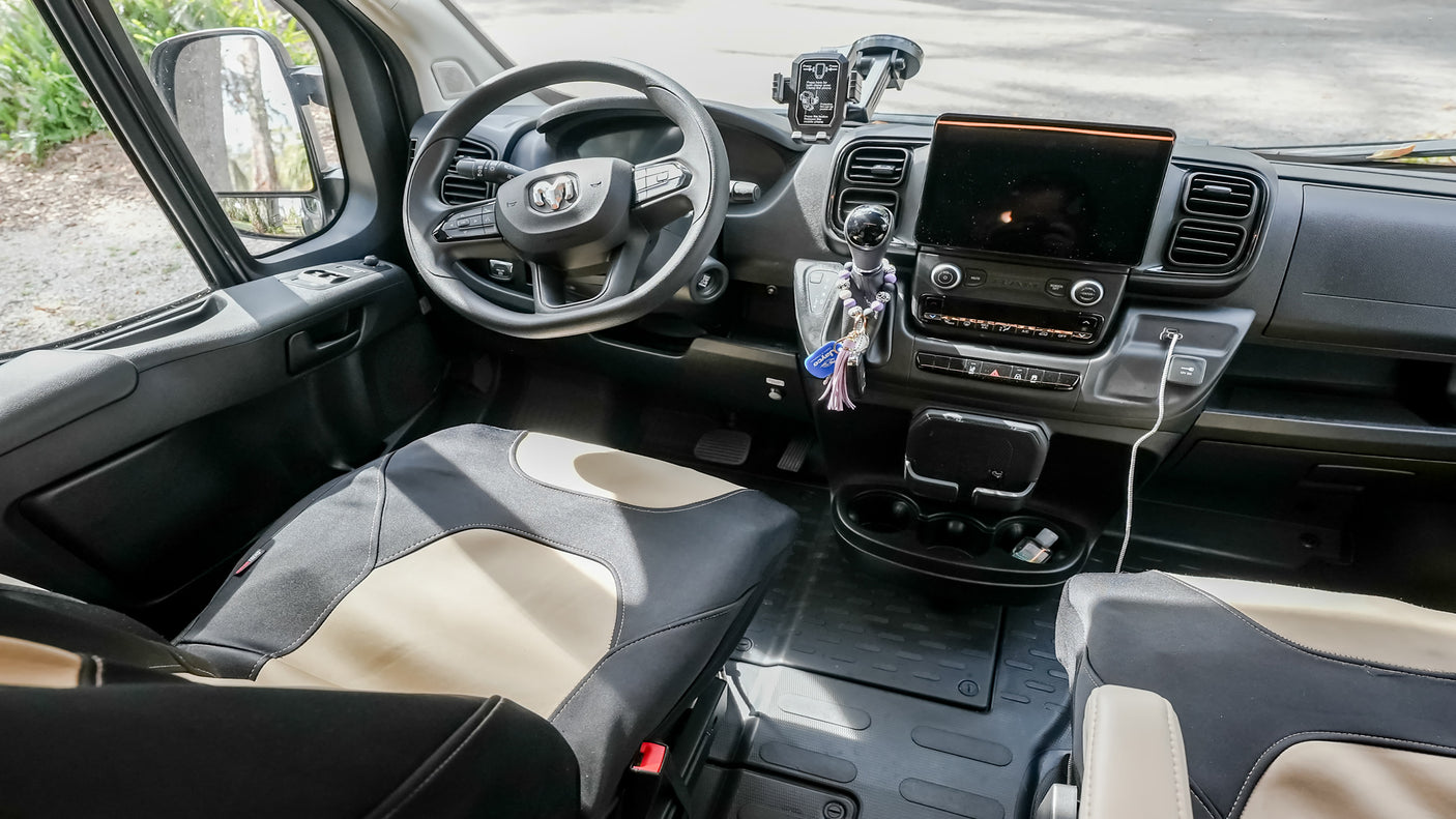 Inside an RV rental's cockpit, showing the modern dashboard, steering wheel, and comfortable front seats for travel.