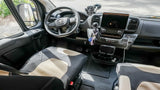 Inside an RV rental's cockpit, showing the modern dashboard, steering wheel, and comfortable front seats for travel.