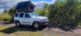 White Nissan Xterra SUV with deployed rooftop tent. Perfect for your RV rental, offering outdoor adventure & camping.