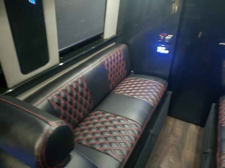 Experience comfort in this RV rental's interior, featuring luxurious black leather seating with red diamond stitching.