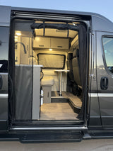 Open-door view of an RV rental's inviting interior: dinette, kitchenette, and storage. Perfect for road trips!