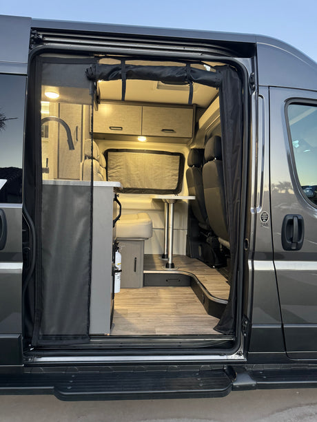 Open-door view of an RV rental's inviting interior: dinette, kitchenette, and storage. Perfect for road trips!
