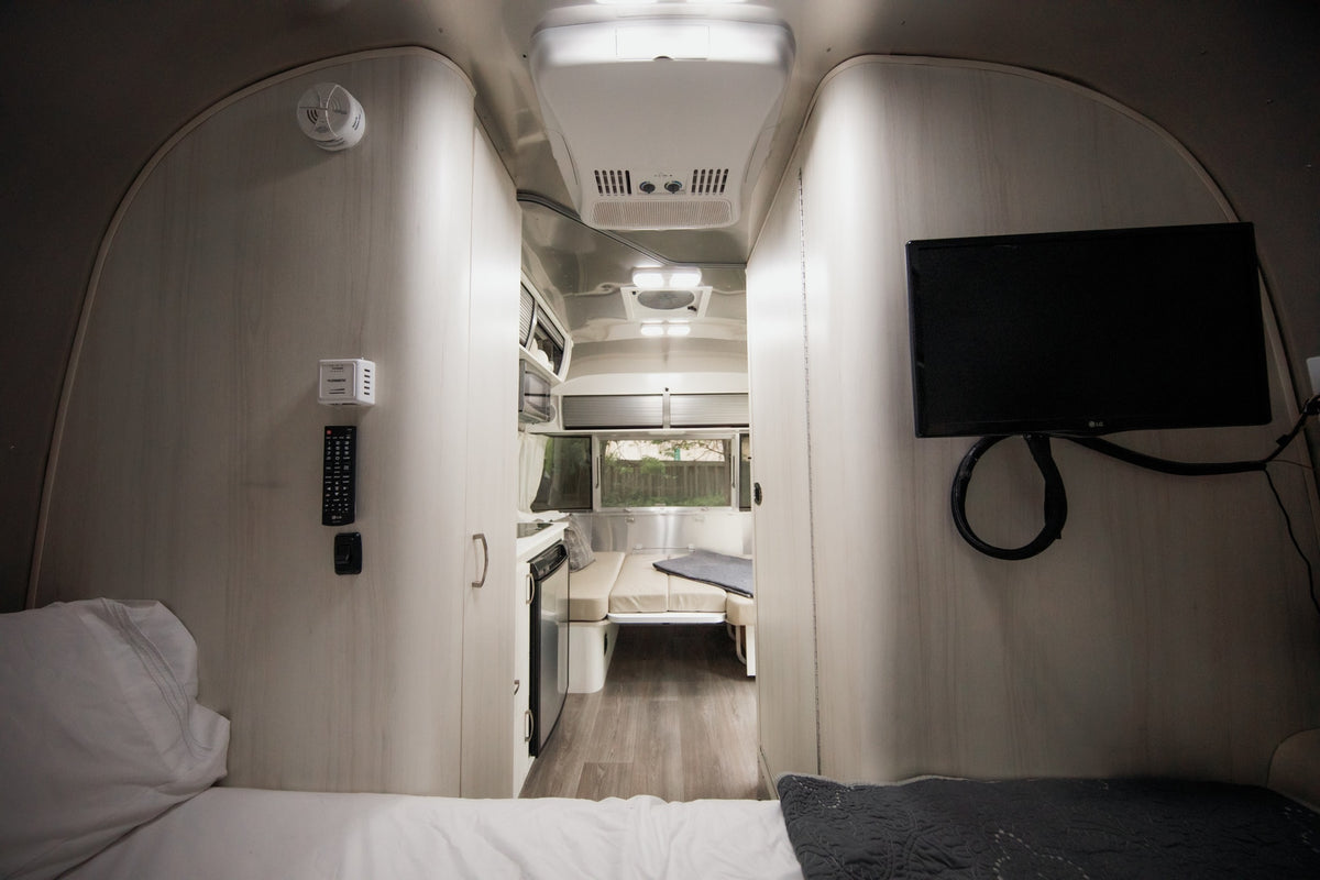 Inside this modern RV rental, find a comfortable bed, compact kitchen, dinette, and TV for your travels. — photo 13