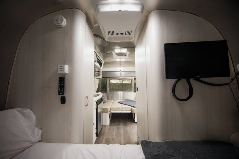 Inside this modern RV rental, find a comfortable bed, compact kitchen, dinette, and TV for your travels. — photo 13