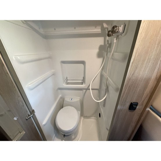  and comfortable seating arranged for an intimate meal.|Smiling man holds a mug in a cozy RV rental. Snacks and a compact kitchen are visible — photo 7
