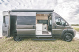 Grey camper van, side open revealing its custom interior, parked oceanside. Perfect for an rv rental adventure.