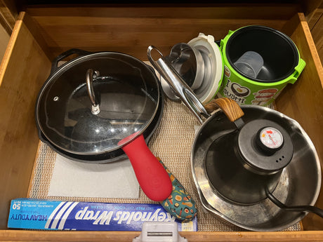 Organized kitchen drawer with cooking essentials: cast iron pot, kettle, and foil, ideal for an RV rental kitchen.