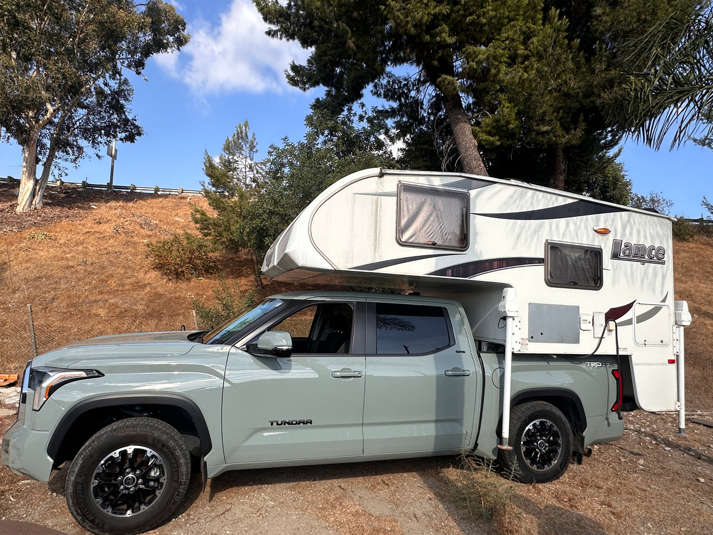 A light green Toyota Tundra pickup truck with a Lance truck camper. Ideal for an RV rental adventure!