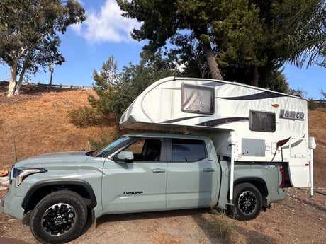 A light green Toyota Tundra pickup truck with a Lance truck camper. Ideal for an RV rental adventure!
