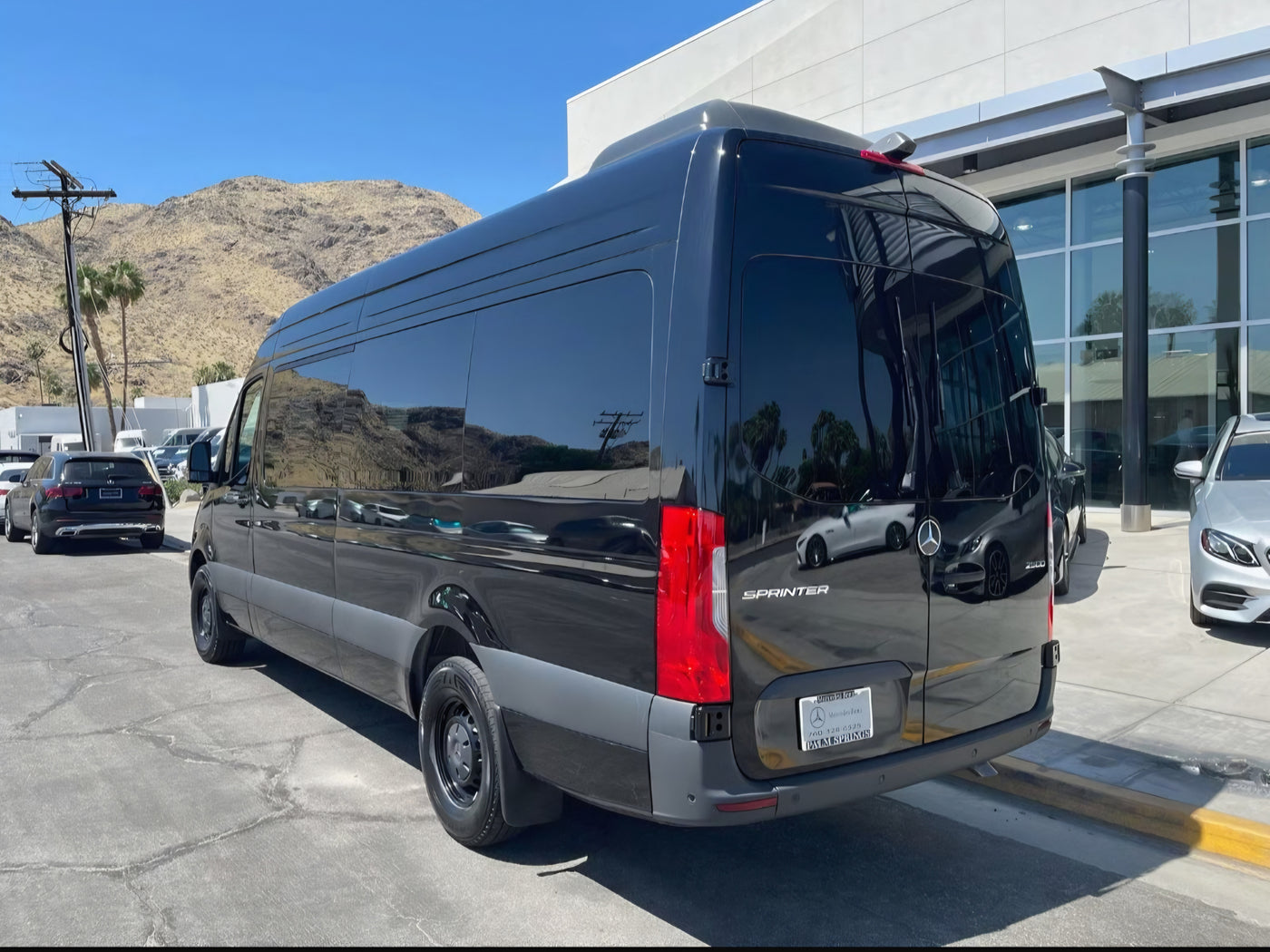 Sleek black Mercedes-Benz Sprinter van, ideal for rv rental, parked at a Palm Springs dealership with mountain views. — photo 3