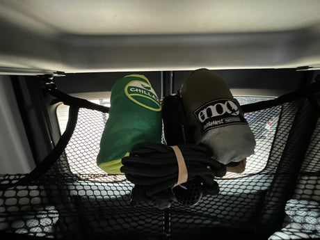 RV rental overhead storage: Chillax & Eno hammocks with rope, secured in a cargo net. Gear organized for travel.