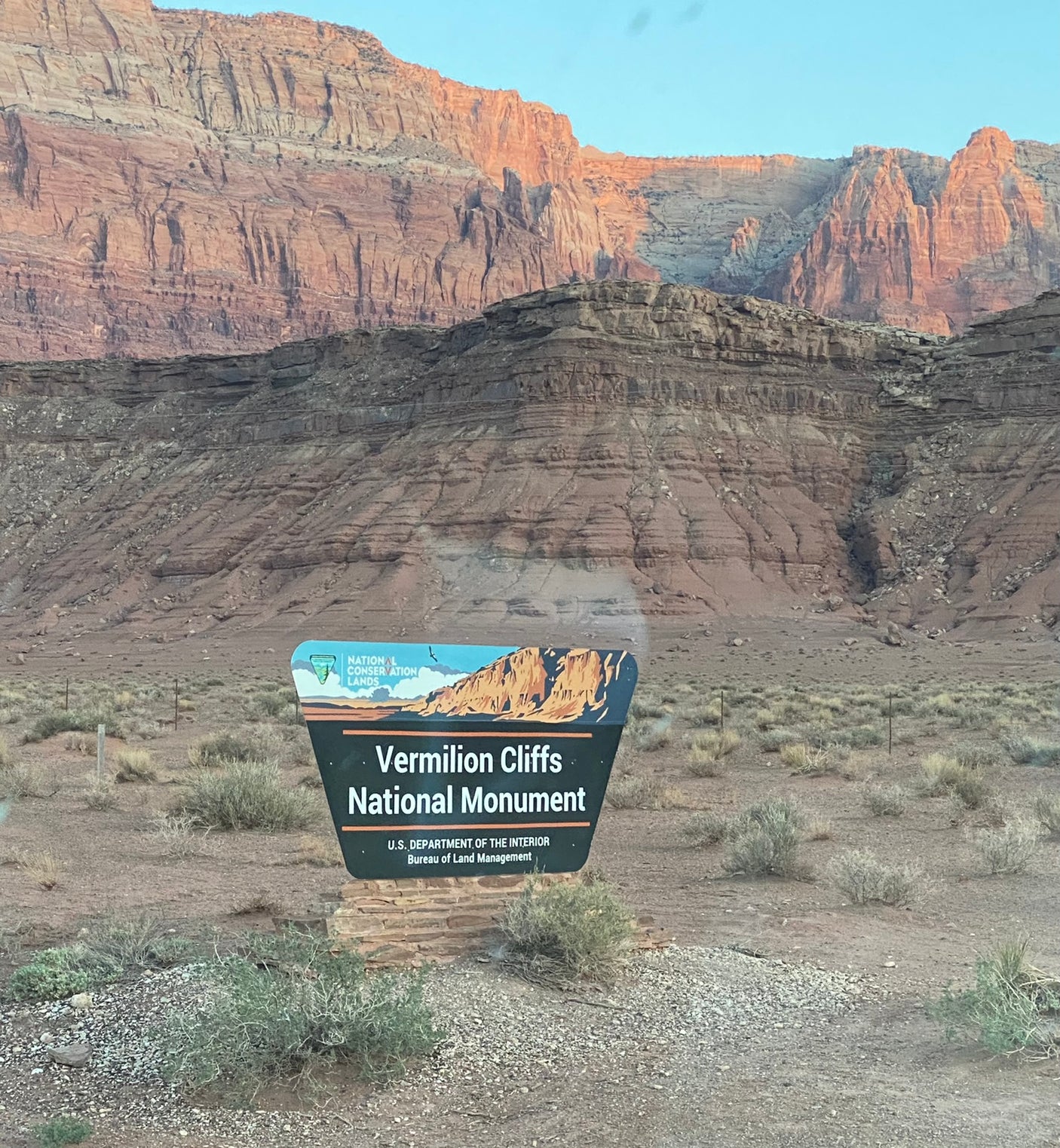 Your rv rental journey begins at Vermilion Cliffs National Monument's welcome sign, surrounded by stunning red rock desert.