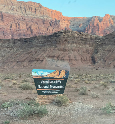 Your rv rental journey begins at Vermilion Cliffs National Monument's welcome sign, surrounded by stunning red rock desert.