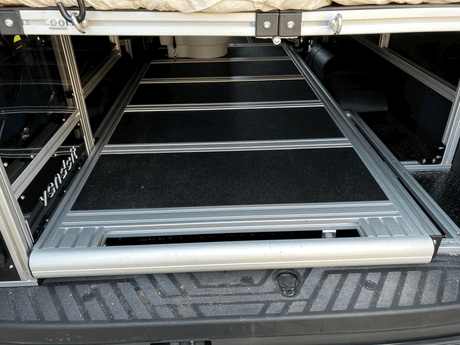 This RV rental’s rear cargo area features a practical pull-out storage system under an elevated bed.