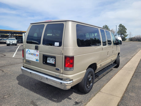 Gold Ford E350 Switchback van rental, suitable for RV rental trips, parked in a storage lot.